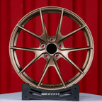 BMW M2 G87 19 inch custom forged wheels | Apex VS-5RS style Satin Bronze finish, straight front view on red backdrop showcasing track-inspired split-spoke design
