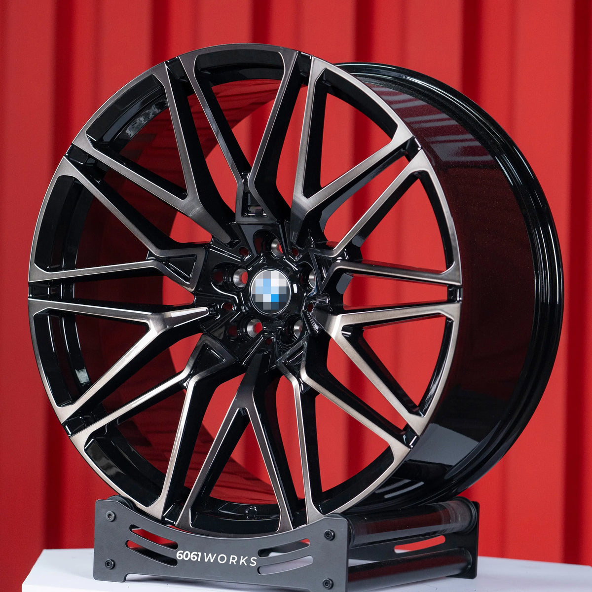 BMW X5 M F95 22 inch custom forged wheels | OEM BMW 818M style Gloss Black with Machined Face Dark Coating, dynamic angled view on display stand showing dark tint clear coat over machined face